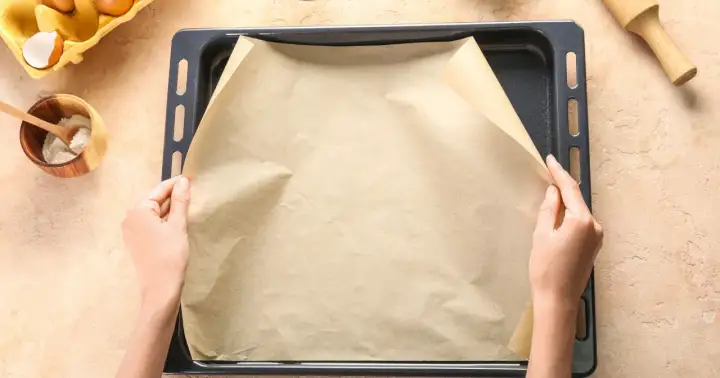 Ręce układają papier do pieczenia na blasze. Zastanawiasz się, czym zastąpić papier do pieczenia?